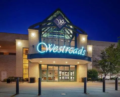 Shopping mall entrance with illuminated signage and canopy at dusk