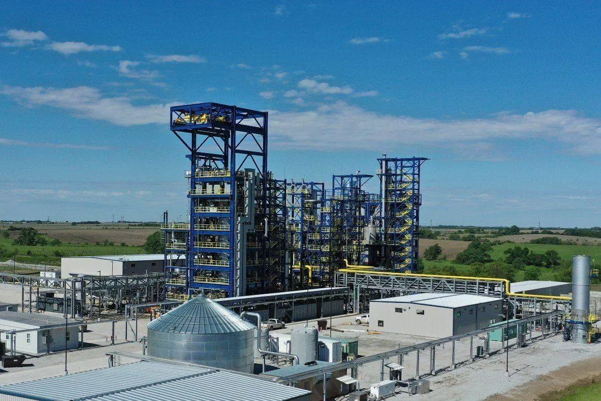 Aerial view of an industrial process facility with blue steel structures, a grain bin and piping